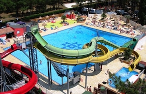 Un parc aquatique doté de nombreux toboggans, d’une piscine centrale et de chaises longues.