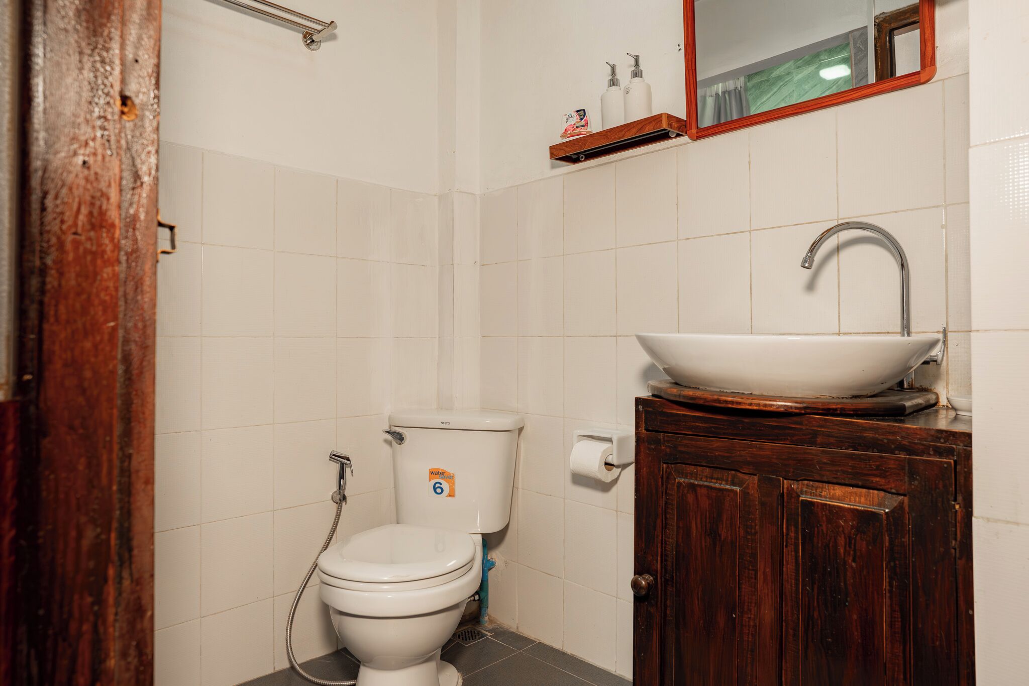 Ein Badezimmer mit Toilette, einem Holzschrank mit Waschbecken und einem Spiegel darüber.