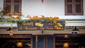 Un café avec une enseigne dans une langue étrangère, des volets en bois et des guirlandes lumineuses.
