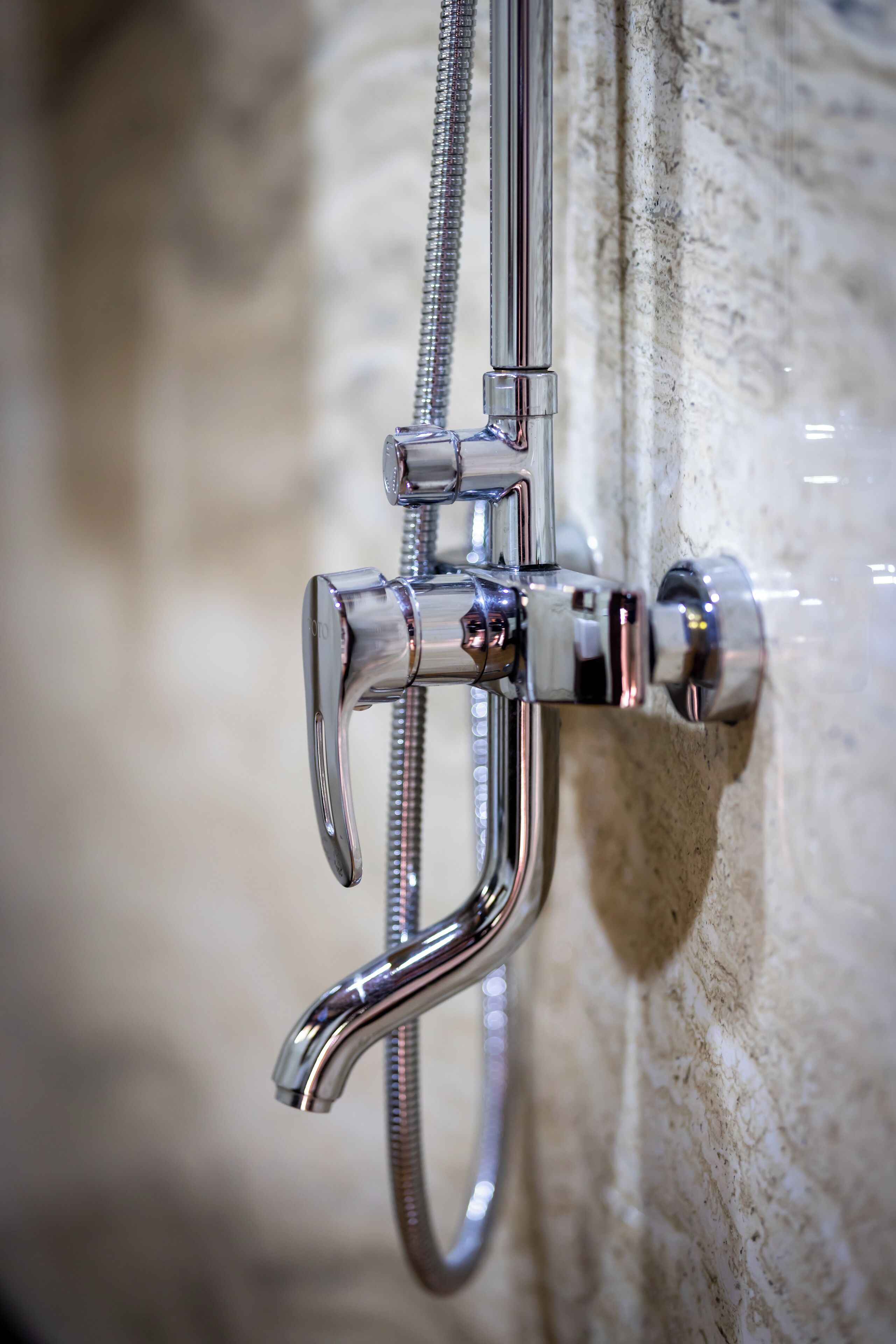 Un cabezal de ducha cromado con una manguera flexible conectada a un grifo de pared.