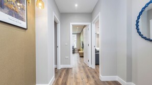 Un couloir doté d’un plancher en bois, de murs blancs et d’une œuvre d’art encadrée représentant « La terrasse du café le soir » de Vincent van Gogh.