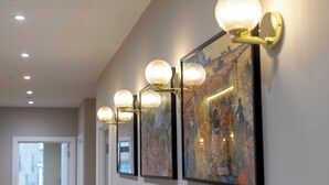 Un couloir avec un luminaire fixé au mur et une œuvre d’art encadrée.