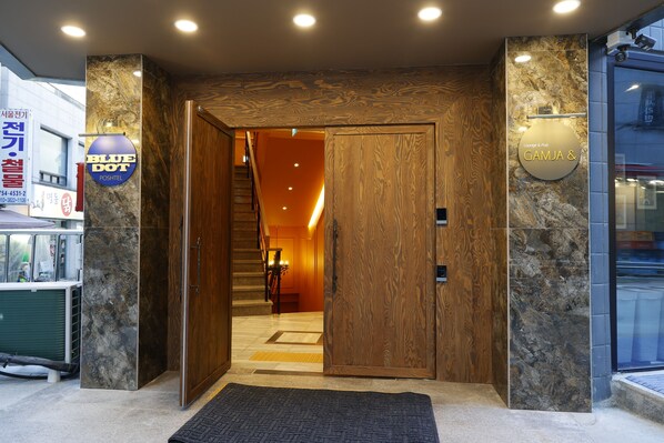 L’entrée d’un hôtel, avec une porte en bois, un comptoir d’accueil et une enseigne indiquant « Blue Dot Postel ».