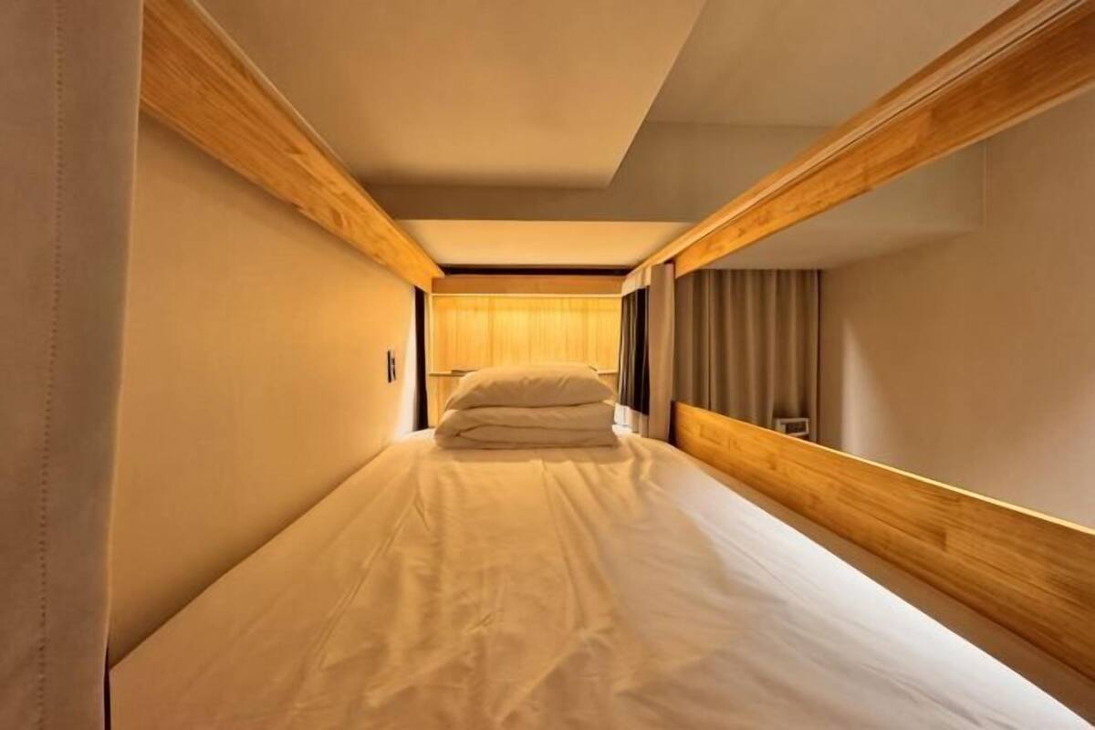 Een kleine kamer met een enkel bed, houten hoofdborden en een bedlampje.