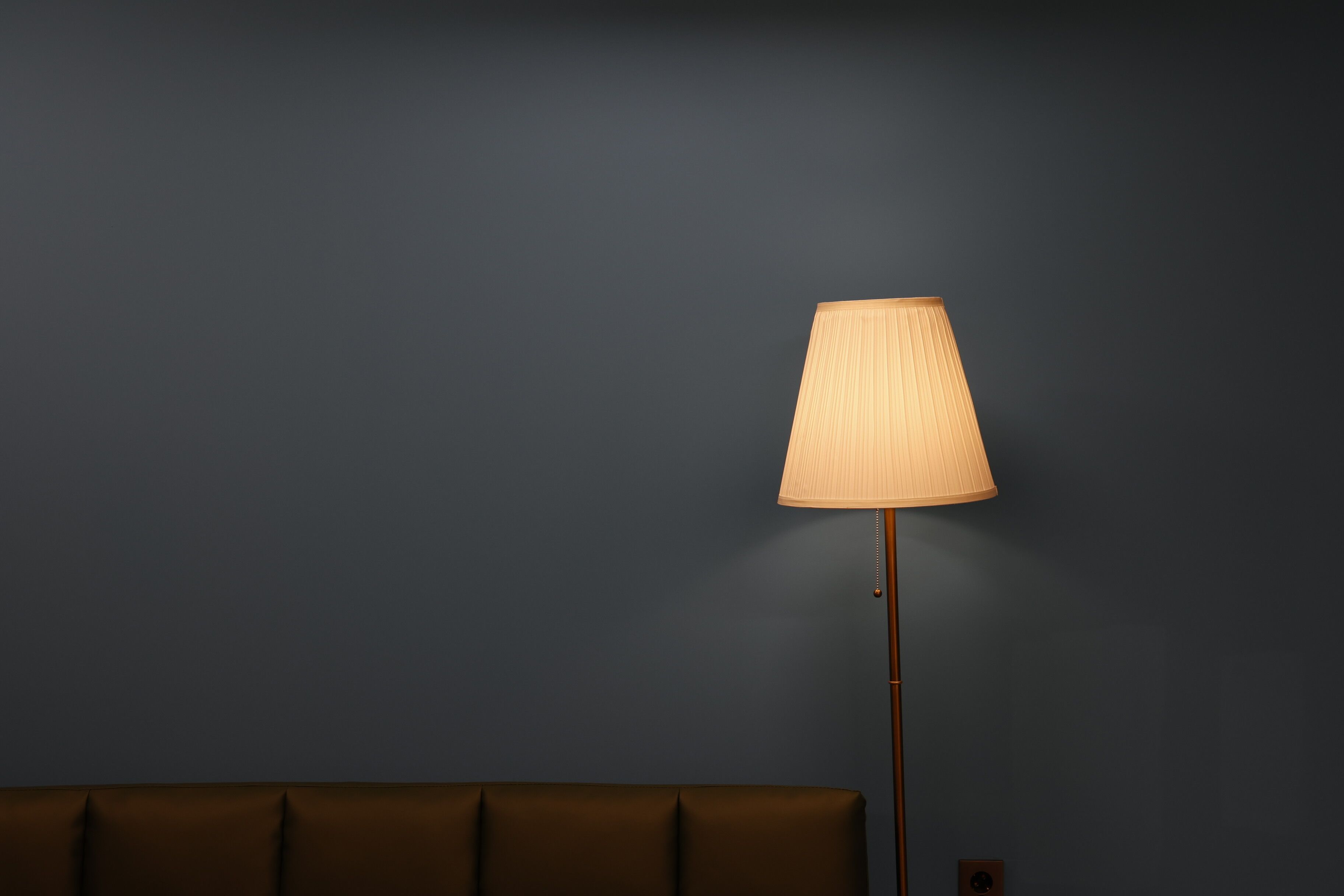Um quarto com parede azul escura e sofá marrom.