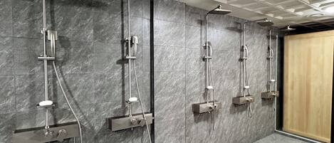 A modern bathroom with multiple showerheads and a marble wall.