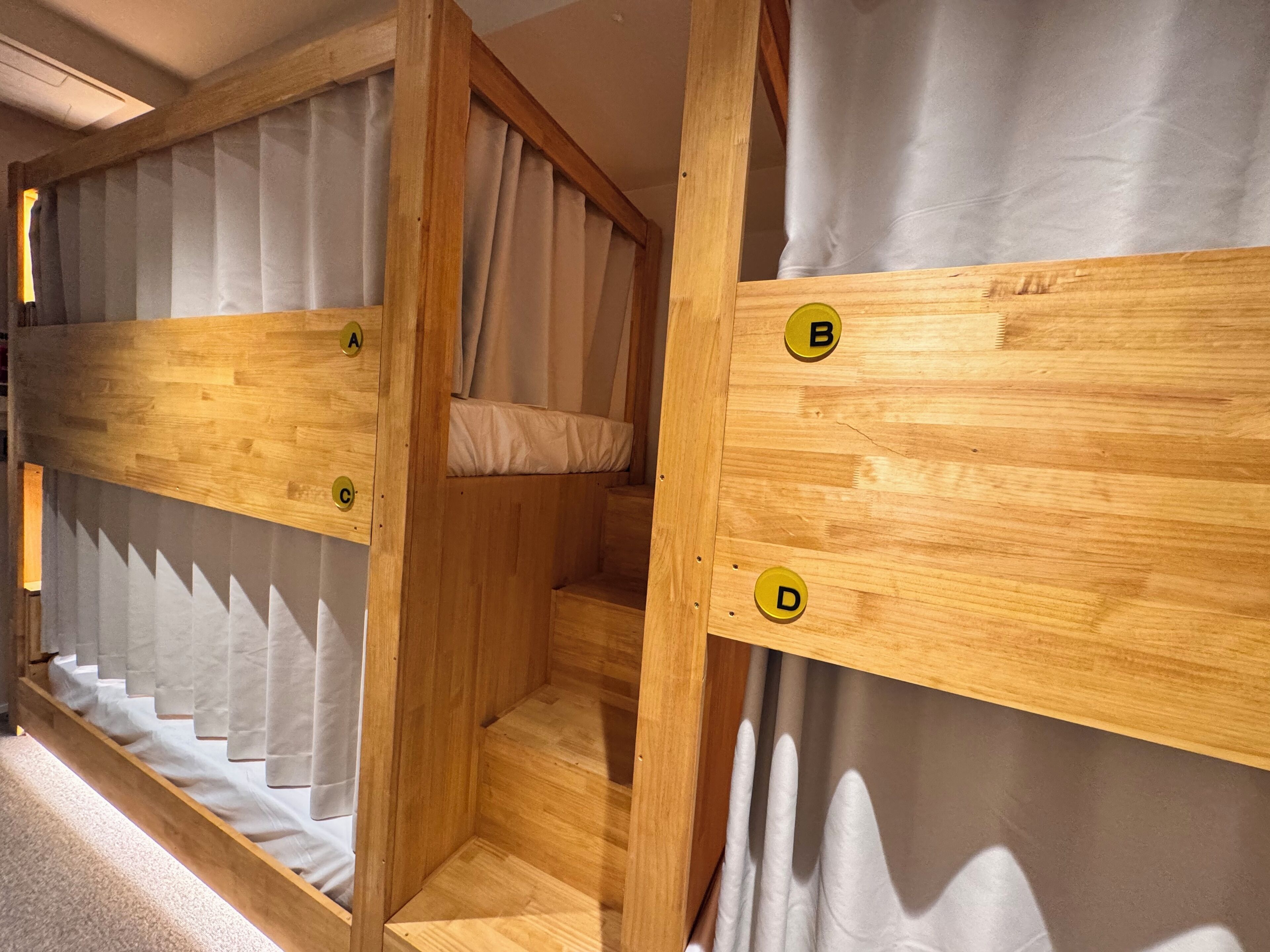 A wooden room with a bunk bed, a small enclosed space, and a curtain.