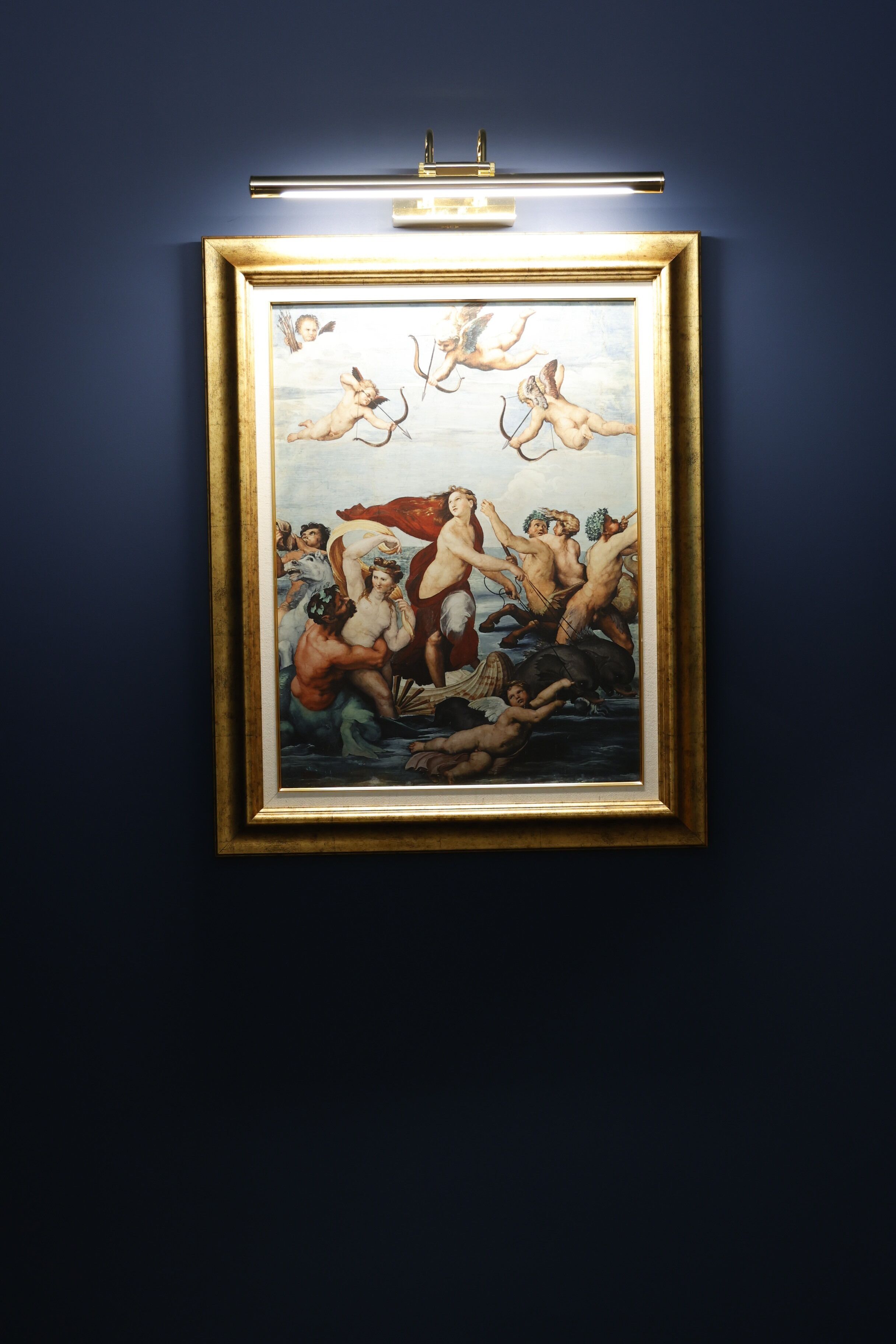 A framed artwork with a classical scene of figures in a dynamic composition, mounted on a wall.
