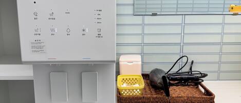 A kitchen counter with a coffee machine, a basket with utensils, and a bottle.