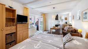 Ein Hotelzimmer mit Bett, Fernseher, Holzmöbeln, einer Küchenzeile und Blick ins Freie.