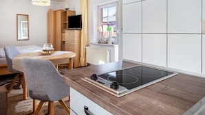 Eine moderne Küche mit eingebautem Herd, Holzschränken und einem Essbereich mit Tisch und Stühlen.