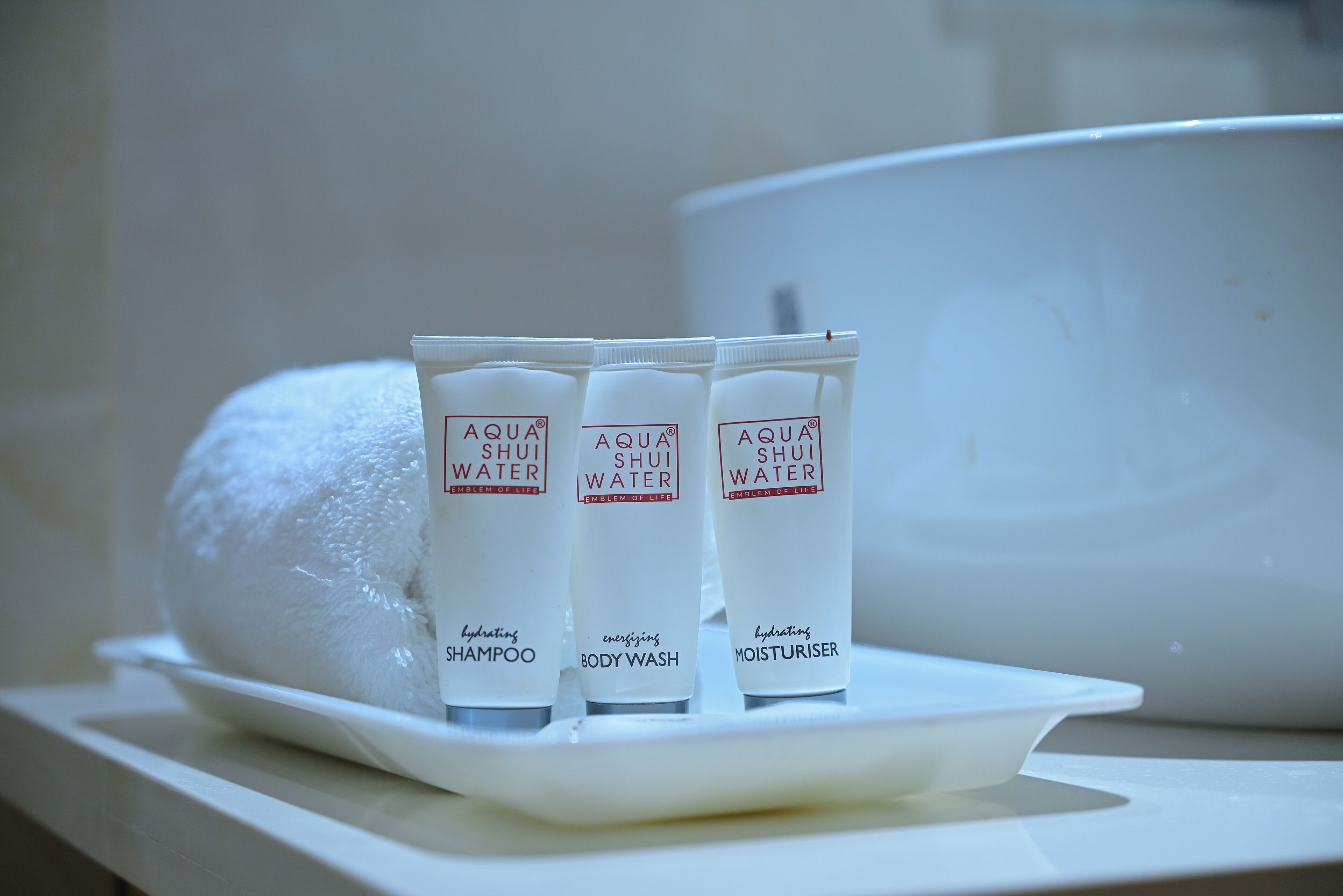 Trois bouteilles d’eau AQUA SHUI sur un plateau blanc.