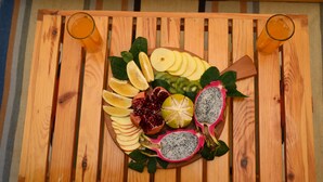 A wooden tray with sliced fruits and two glasses of orange juice.