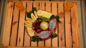 A wooden table with a fruit platter and two glasses of orange juice.