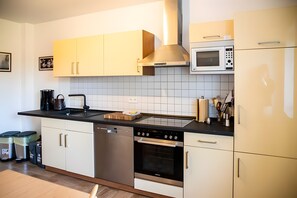 Une cuisine moderne dotée d’appareils électroménagers en acier inoxydable, de meubles blancs et d’un dosseret carrelé.