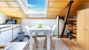 A compact kitchen with a skylight, white cabinets, a microwave, and a dining table with chairs. - Studio 'Alte Schmiede' with Wi-Fi and Air Conditioning (Kuden)
