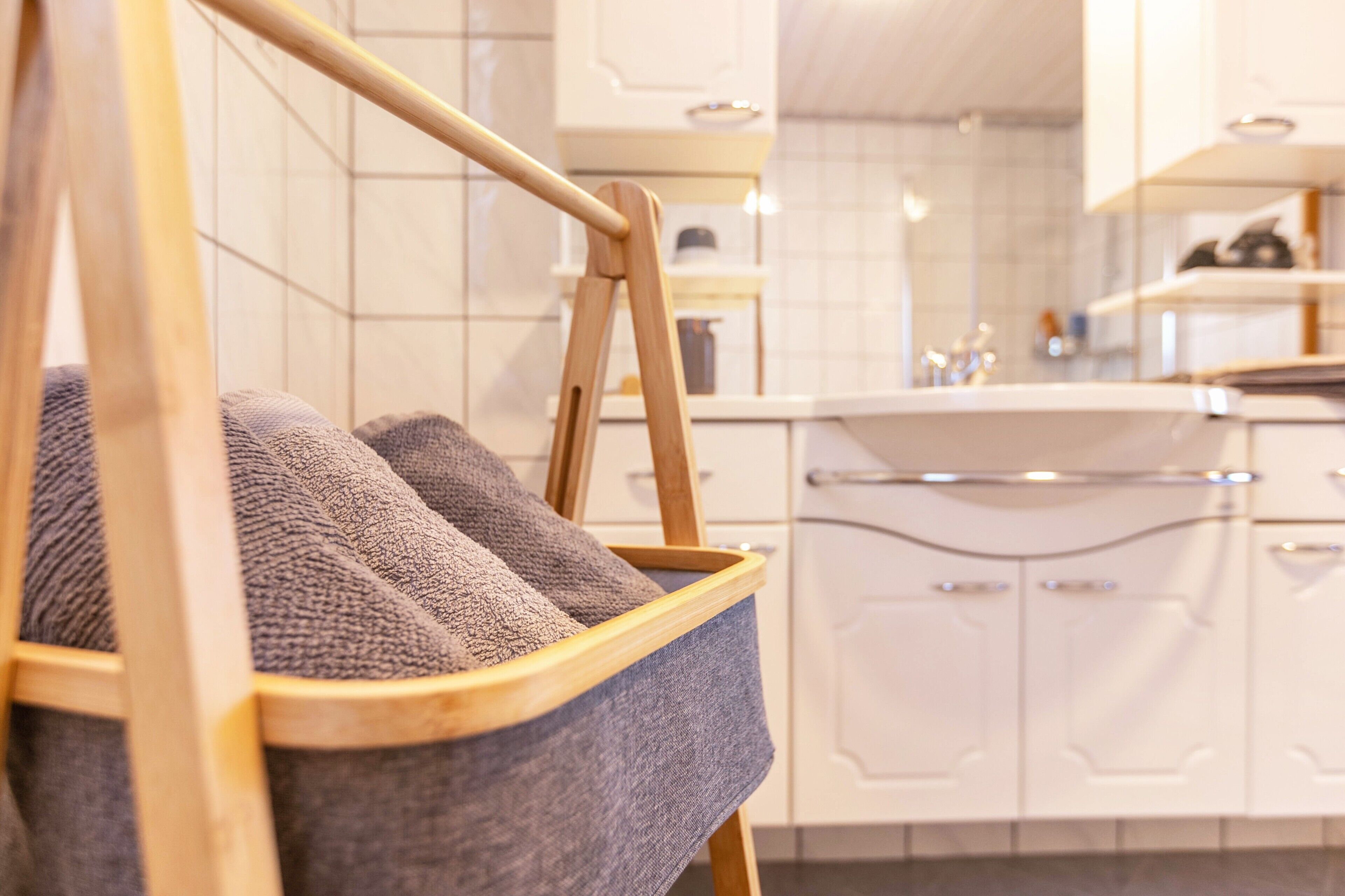 Ein Holzstuhl mit blauer Sitzkissen in einer modernen Küche mit weißen Schränken und einem Spülbecken.