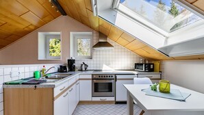 A modern kitchen with a skylight, white cabinets, a stove, and a dining area with a table. - Studio 'Alte Schmiede' with Wi-Fi and Air Conditioning (Kuden)