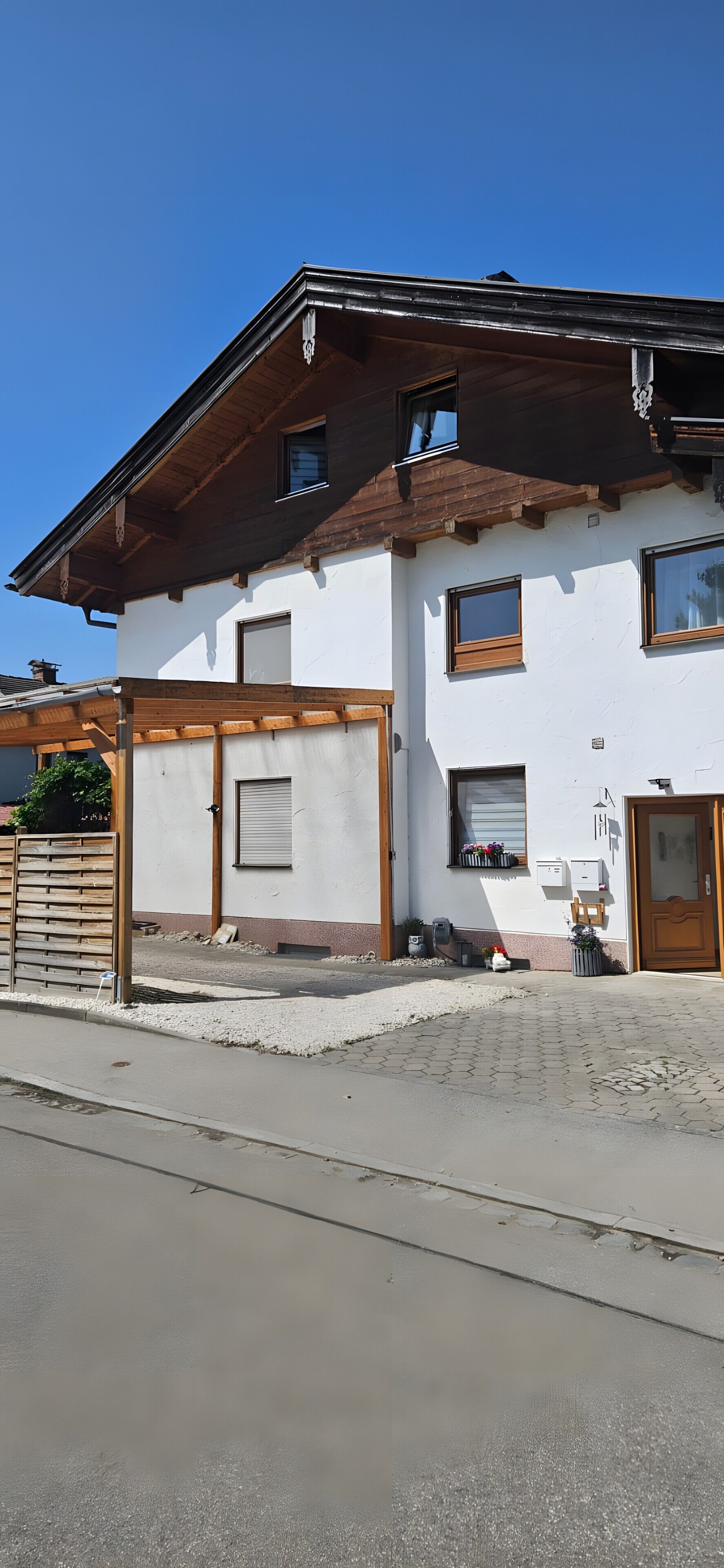 A two-story building with a wooden facade, a garage door, and a small porch area.
