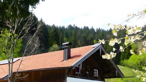 Eine rustikale Chalet mit rotem Ziegeldach, Steinunterbau und einer Holzdiele.