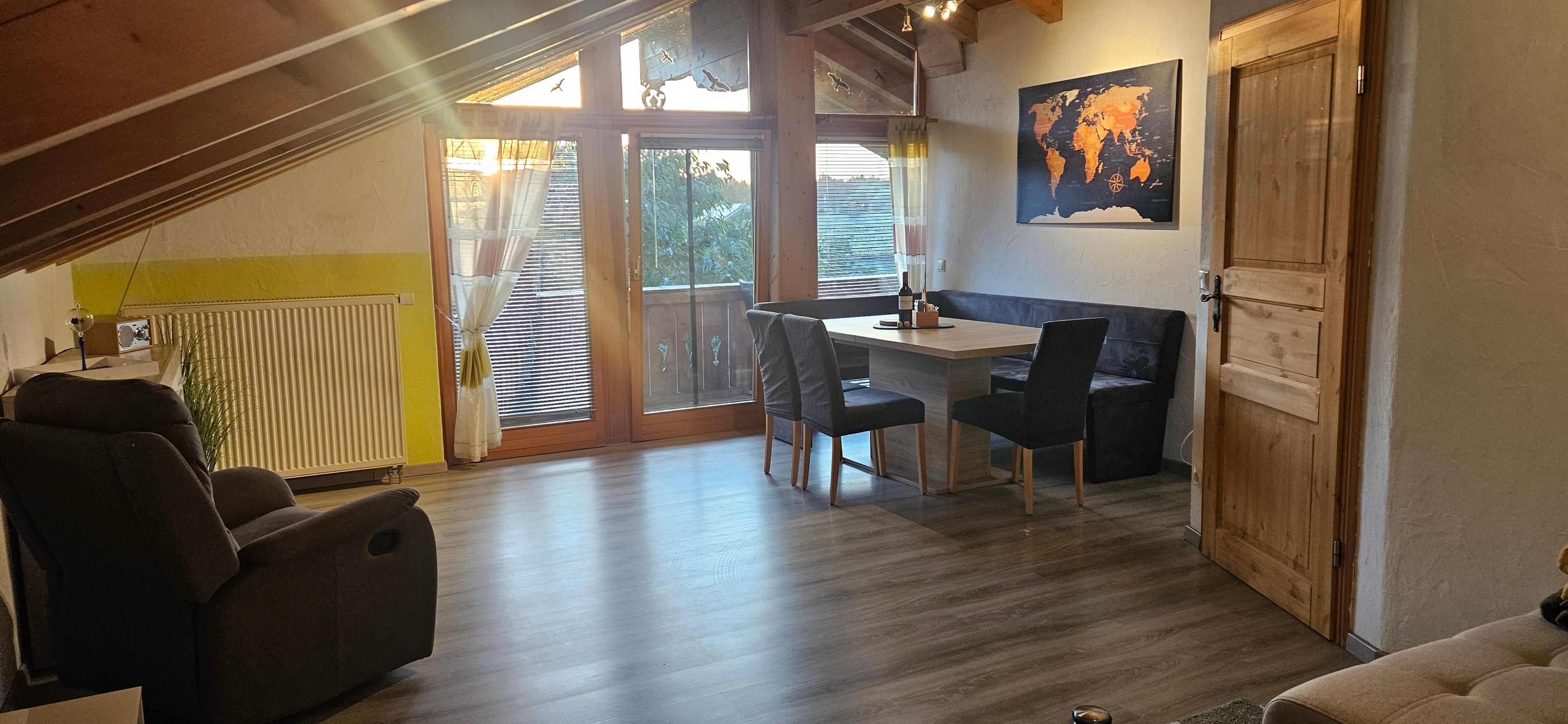 Un comedor con una mesa, sillas, un radiador y un mapa mundial en la pared.