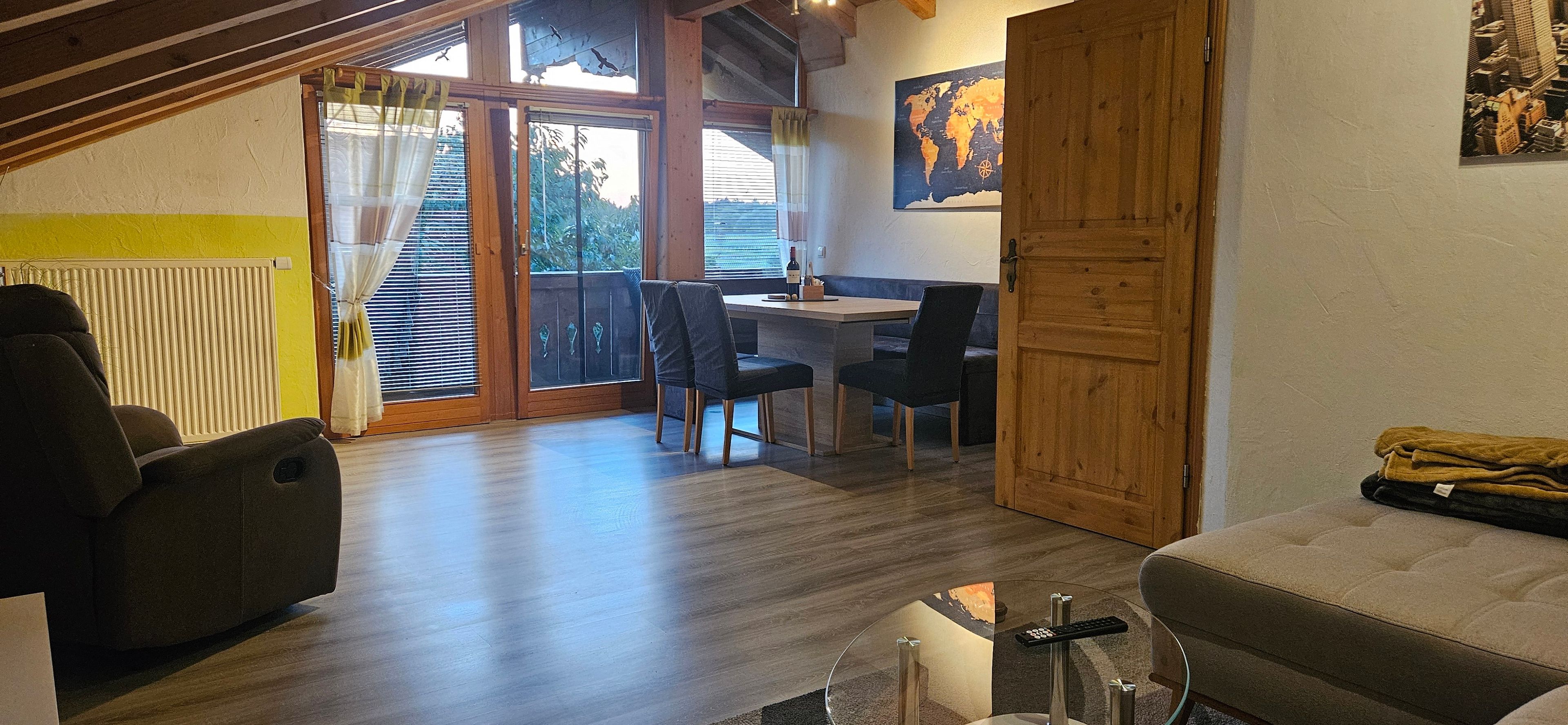 A cozy living area with a sofa, a dining table with chairs, and a wooden door.