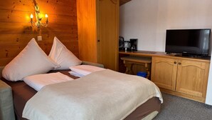 A wooden room with a bed, pillows, a television, a coffee maker, and a cabinet. - Apartment '1' with Mountain View, Shared Terrace and Wi-Fi (Leutasch)