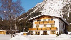 A multi-story hotel with a balcony, surrounded by snow-covered mountains. - Apartment '1' with Mountain View, Shared Terrace and Wi-Fi (Leutasch)