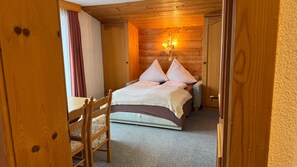 Un dormitorio con paneles de madera, una cama, una silla y una mesita de noche.