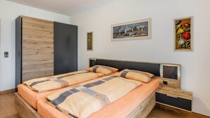 A bedroom with a bed, a wardrobe, a bedside table, and two framed pictures on the wall. - Apartment 'Westerdeich' with Private Terrace, Shared Garden and Wi-Fi (Westerdeichstrich)