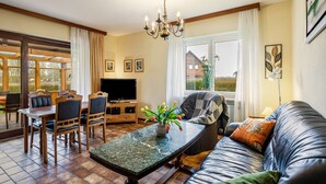 A living room with a dining table, chairs, a sofa, a TV, and a chandelier. - Apartment 'Westerdeich' with Private Terrace, Shared Garden and Wi-Fi (Westerdeichstrich)