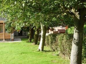 Ein Wohngebiet mit einer Holzterrasse, einem Ziegelhaus und einem gepflegten Rasen.