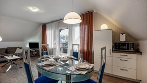 Eine moderne Küche mit Mikrowelle, einem Esstisch für vier Personen und einem großen Fenster mit Vorhängen.