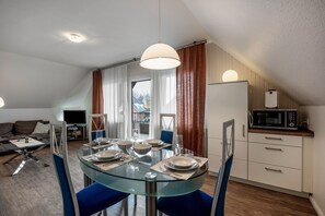 Une cuisine moderne équipée d’un four à micro-ondes, d’une table à manger pour quatre personnes et d’une grande fenêtre avec des rideaux.