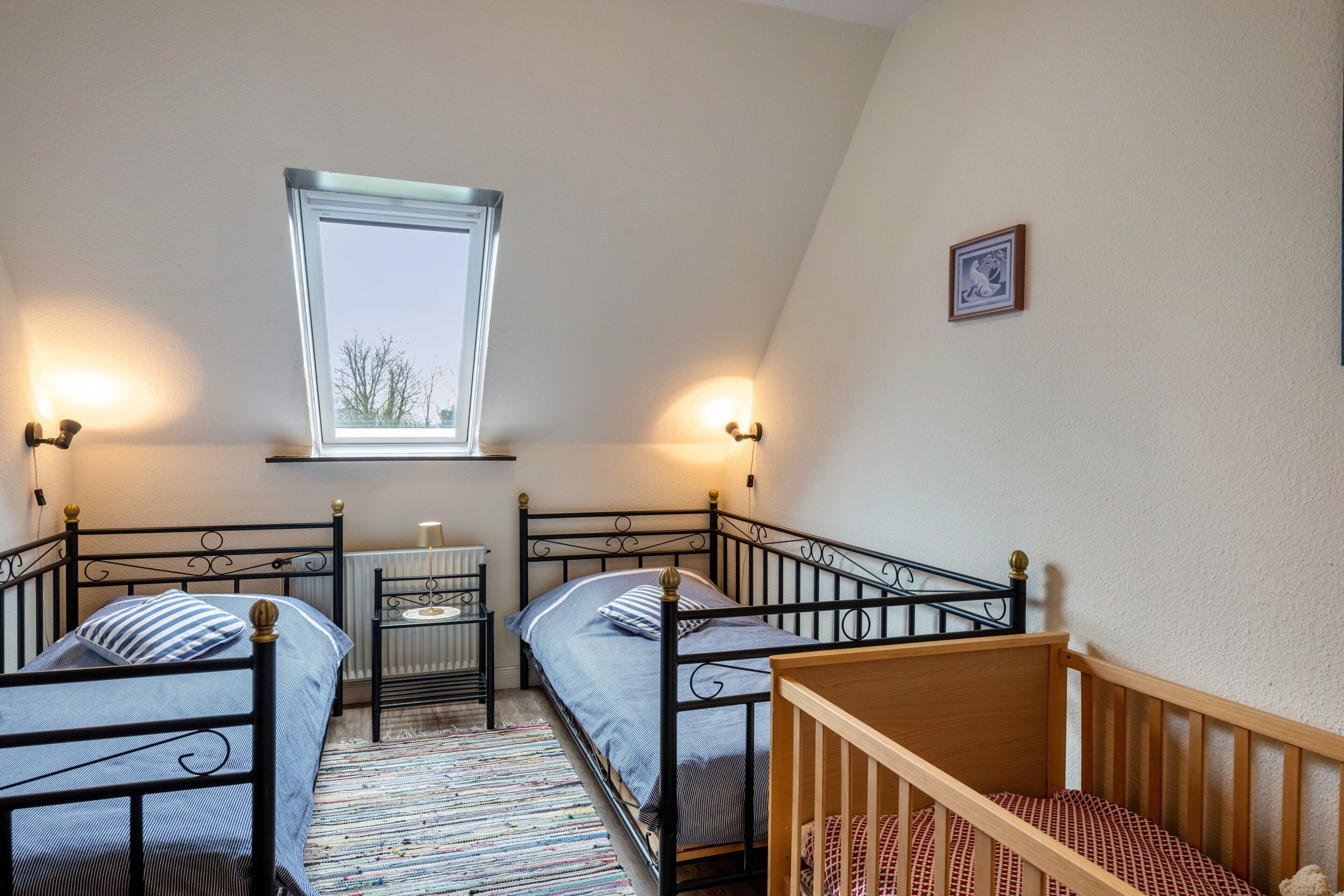 Une chambre de dortoir avec deux lits, une fenêtre, un radiateur et un berceau.