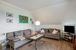 Una sala de estar moderna con dos sofás, una mesa de centro, un televisor y una estantería.