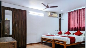 Une chambre à coucher avec un lit en bois, des oreillers rouges, un ventilateur de plafond et un appareil de climatisation.