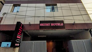 Un hôtel à plusieurs étages au design moderne, avec une enseigne bien visible indiquant « SKYRY HOTELS » au niveau du rez-de-chaussée.