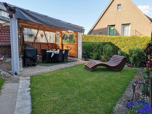 A patio with a table and chairs, a covered barbecue area, and a wooden bench. - Apartment 'Steinbühlschlössle' with Shared Terrace, Shared Garden and Wi-Fi (Schönwald im Schwarzwald)