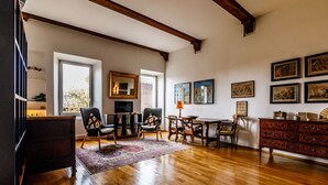 A spacious living room with hardwood floors, a fireplace, a dining area, and a collection of framed artworks on the walls. - GuestHost - Porta Romana Charme Apartment (Siena)