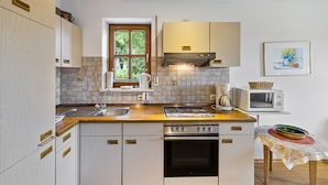 A kitchen with a wooden countertop, stainless steel appliances, and a window with a view of greenery.