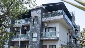 Un edificio moderno de varios pisos con balcones, unidades de aire acondicionado y plantas en macetas.