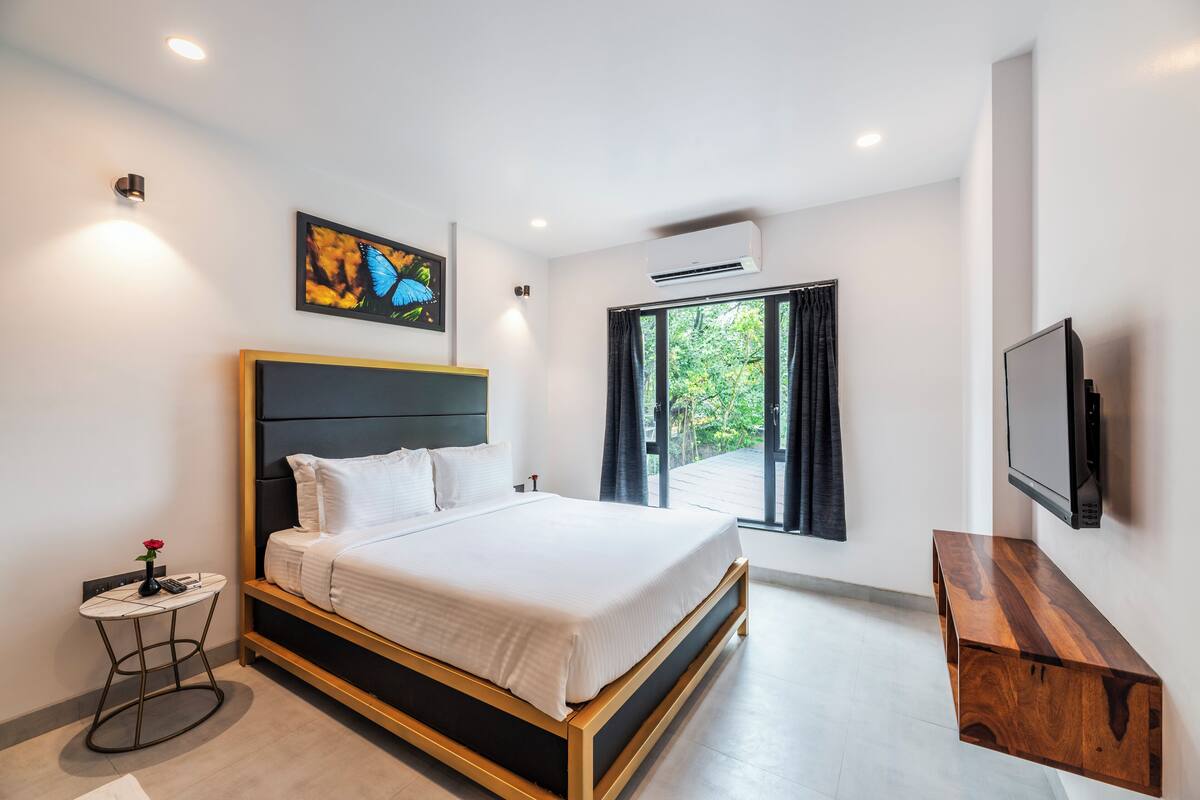 Una camera da letto moderna con un letto grande, un tavolino, una TV a parete e una finestra con tende.