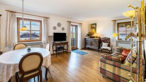 A living room with a round table, a sofa, a television, and a lamp. - Apartment 'Kauderer - Wohnung 2' with Private Terrace, Shared Garden and Wi-Fi (Waging am See)