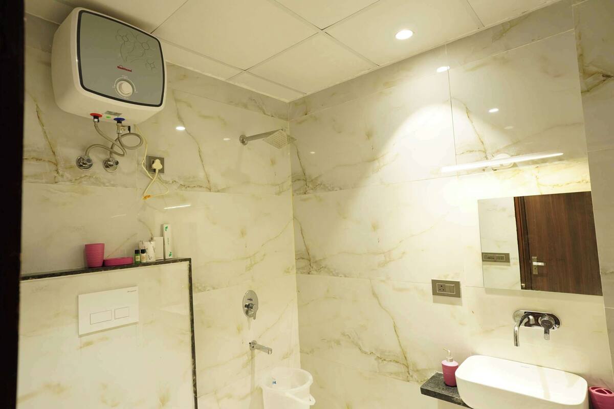 A modern bathroom with a marble wall, a built-in shower, a vanity with a sink, and a mirror.