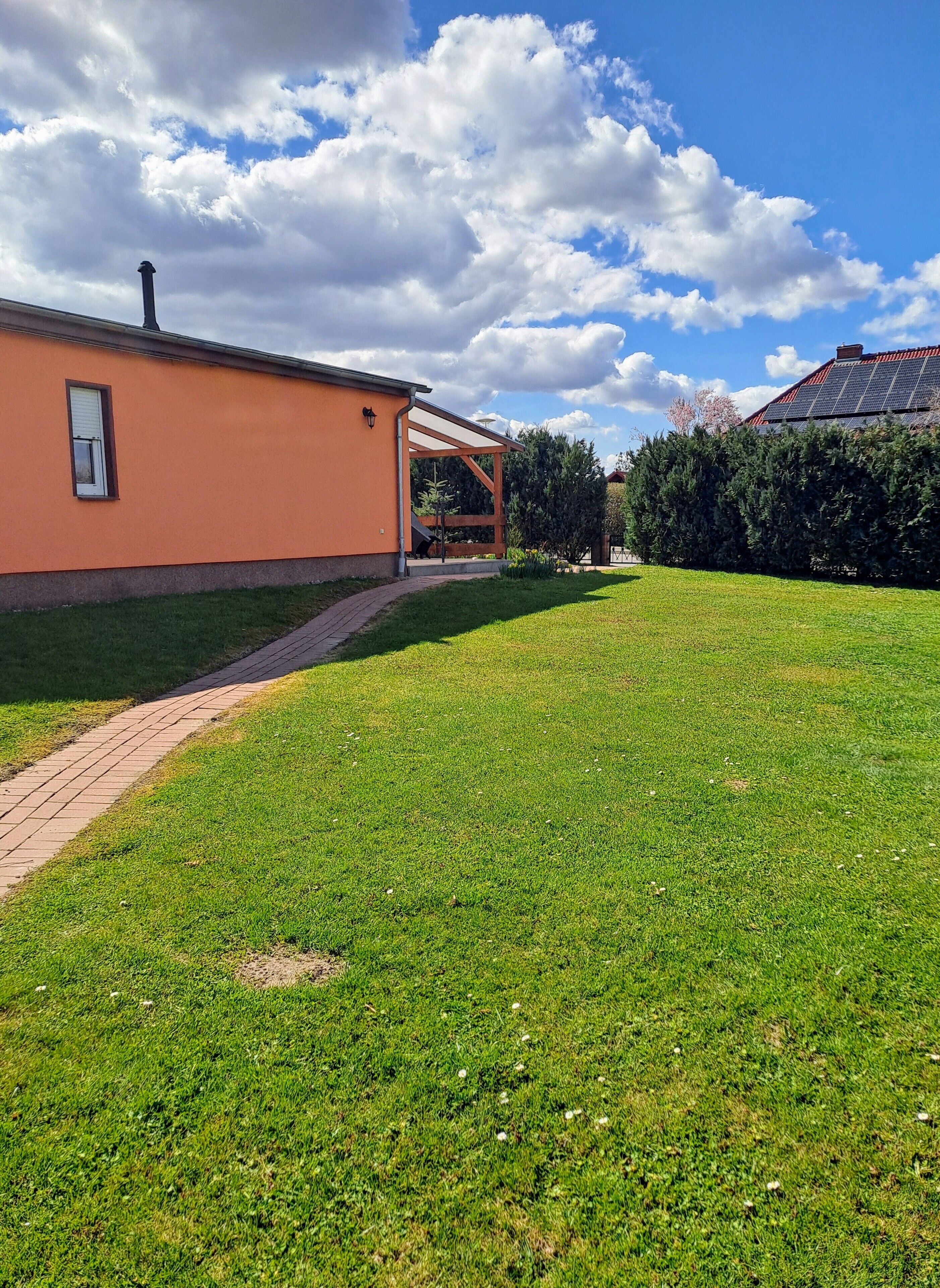 A house with a covered porch, a paved pathway, and a well-maintained lawn.