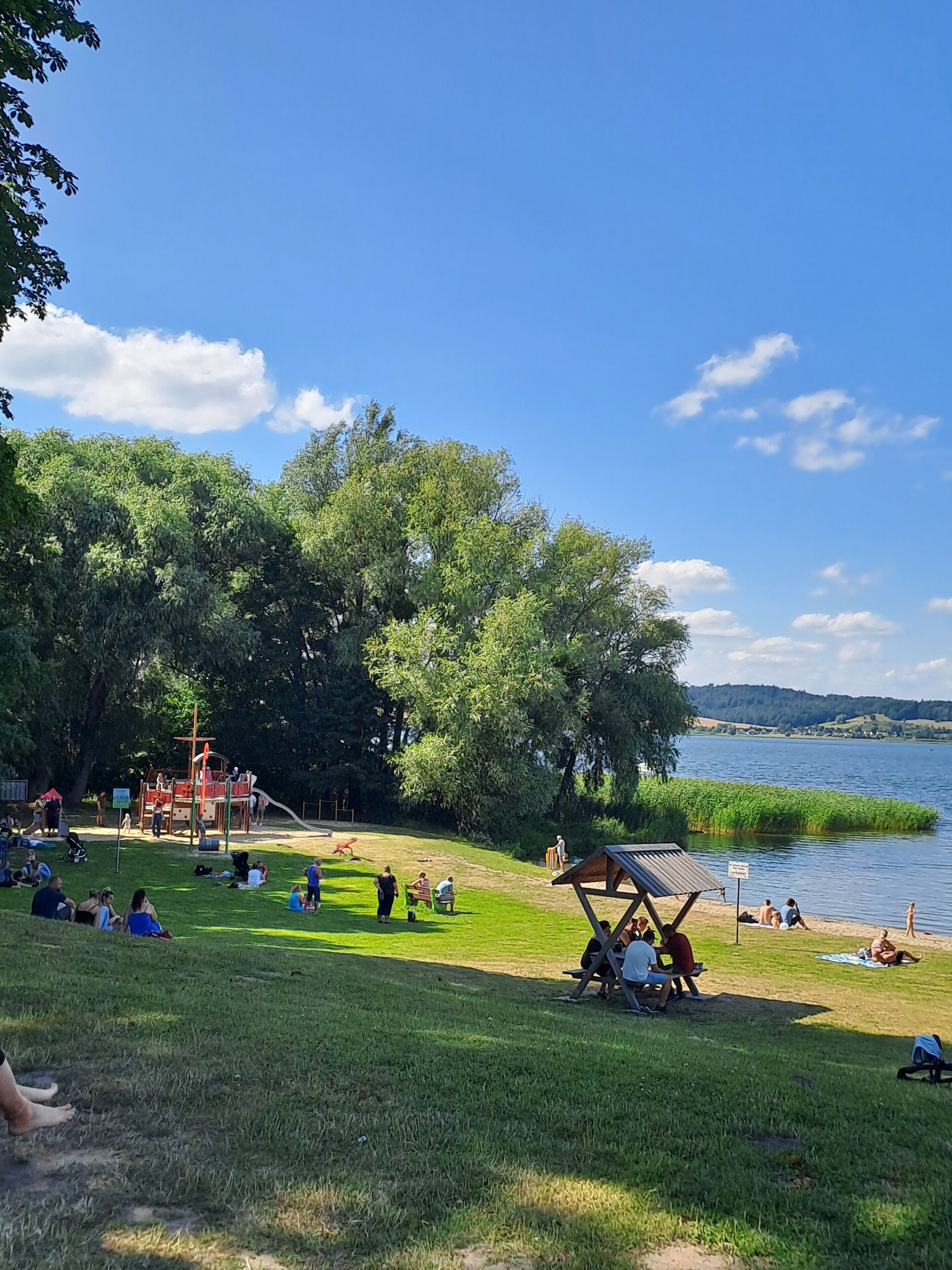 Puisto, jossa on leikkikenttä, nurmialueita ja järvi.