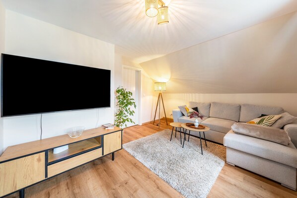 Un salon moderne avec un téléviseur à écran plat, un canapé, une table basse et une lampe.