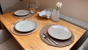 Una mesa de madera con dos platos, cubiertos y un florero con una flor.