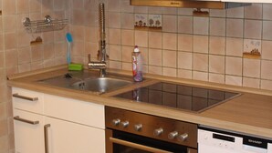 Une cuisine équipée d’un évier, d’une cuisinière, d’un four, d’un lave-vaisselle et de meubles de rangement blancs.